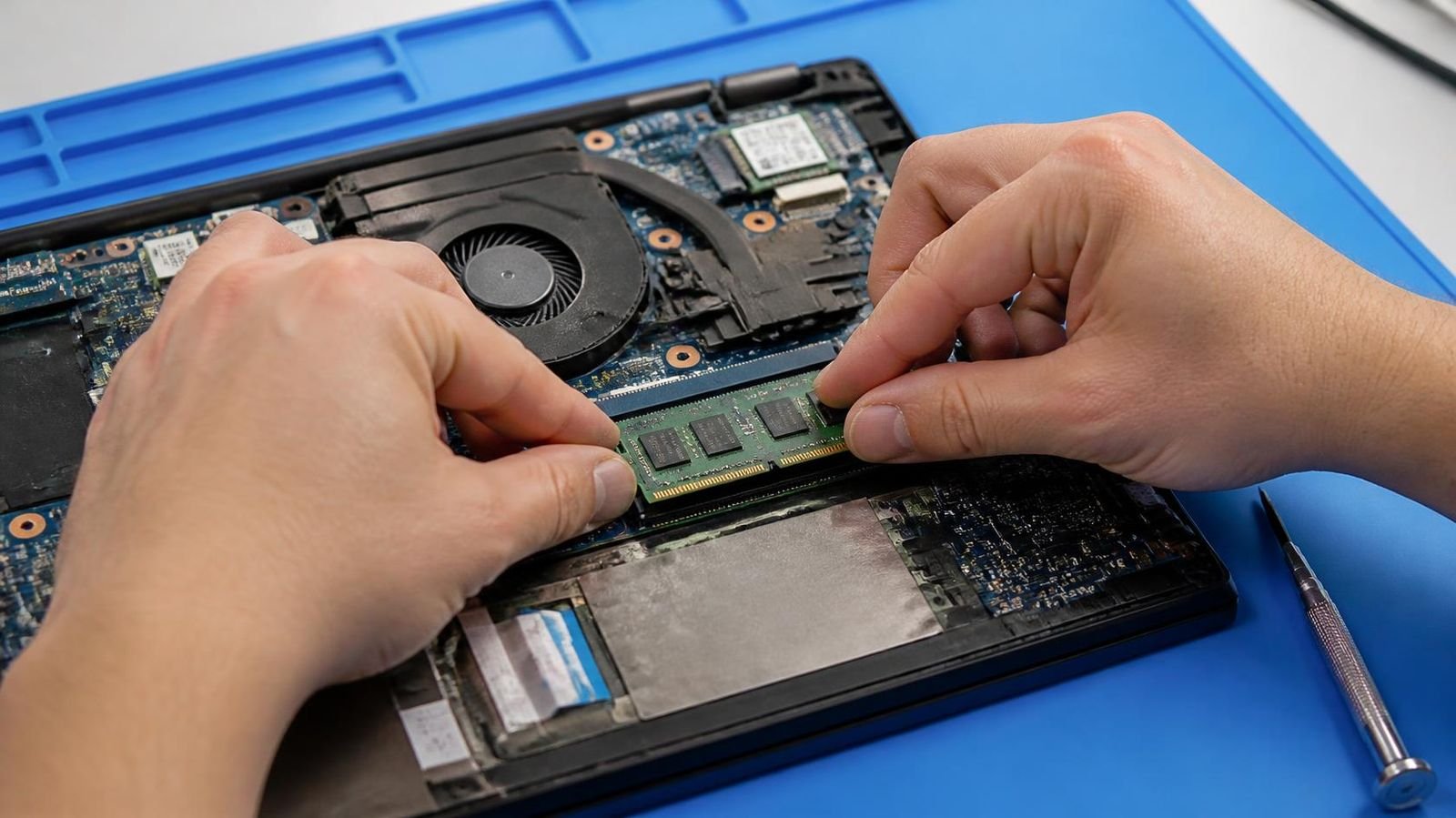 Manos de un técnico instalando un módulo SO-DIMM en un portátil abierto